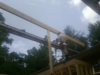 Carpenter setting a ridge beam over a new addition frame — Ice Dam Removal by Roofing Brothers in Eagle Grove
