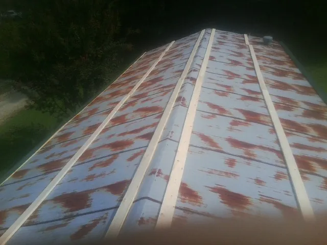 Rusted metal roof panels with new wood purlins before replacement — Storm Damage Roof Repair in Eagle Grove by Roofing Brothers