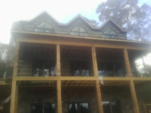 Dormers and porch framing on a large log home under construction — Roof Coating work by our crew in Eagle Grove