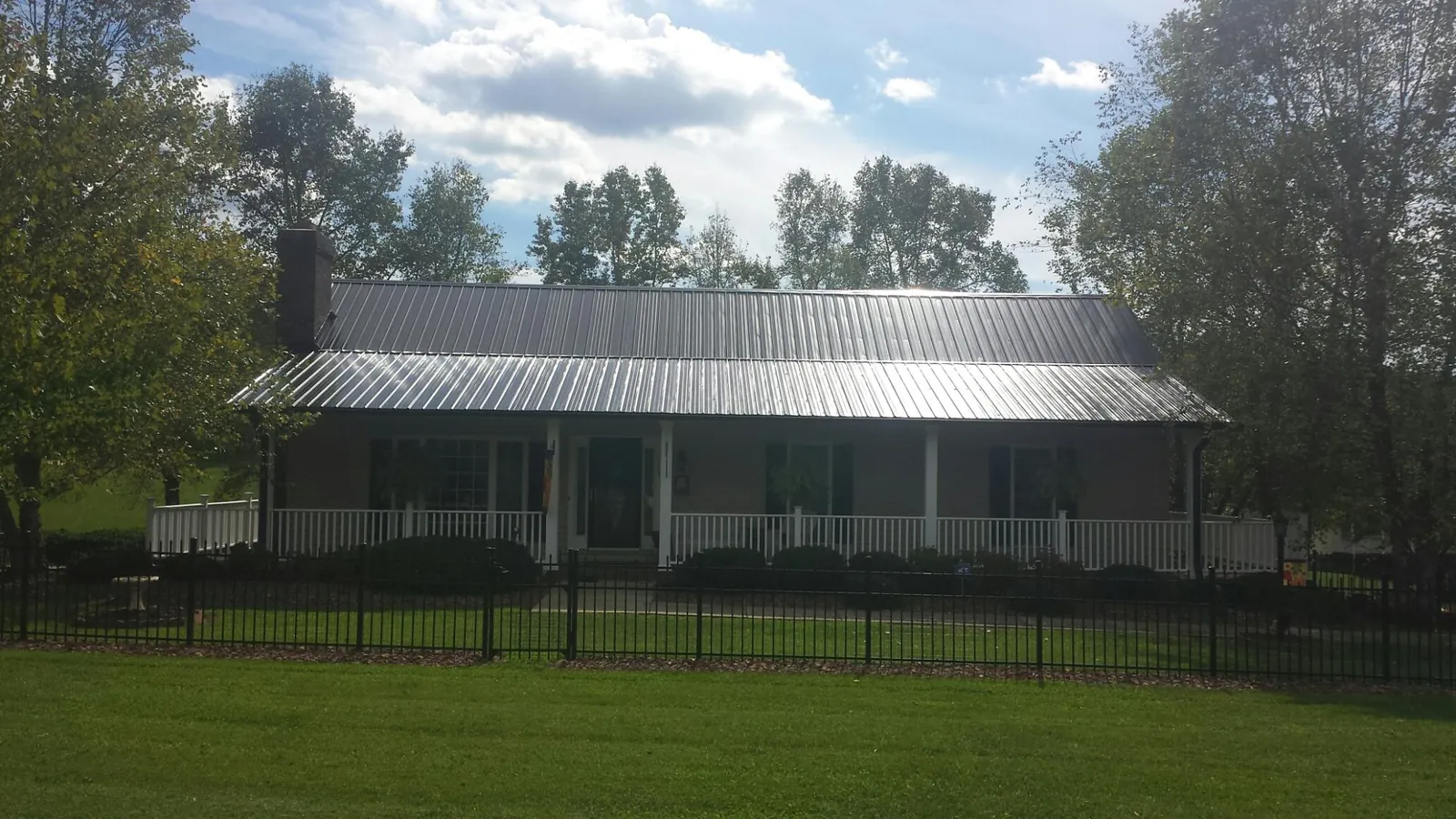 Gray metal roof on a brick ranch with a full width front porch — Gutter Guard Installation work by our crew in Eagle Grove