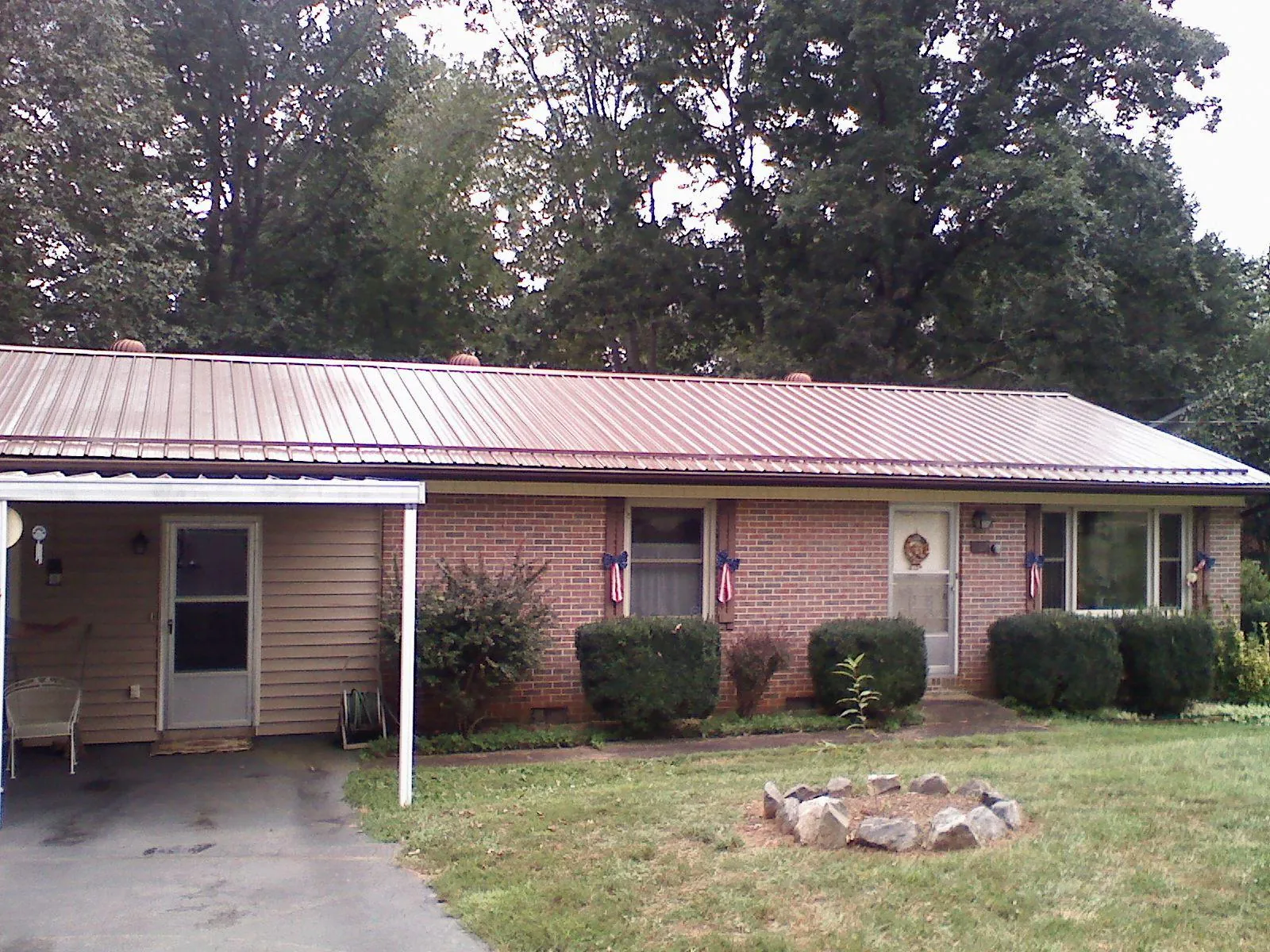 Bronze metal roof and carport on a brick ranch home — Roof Repair work by our crew in Eagle Grove