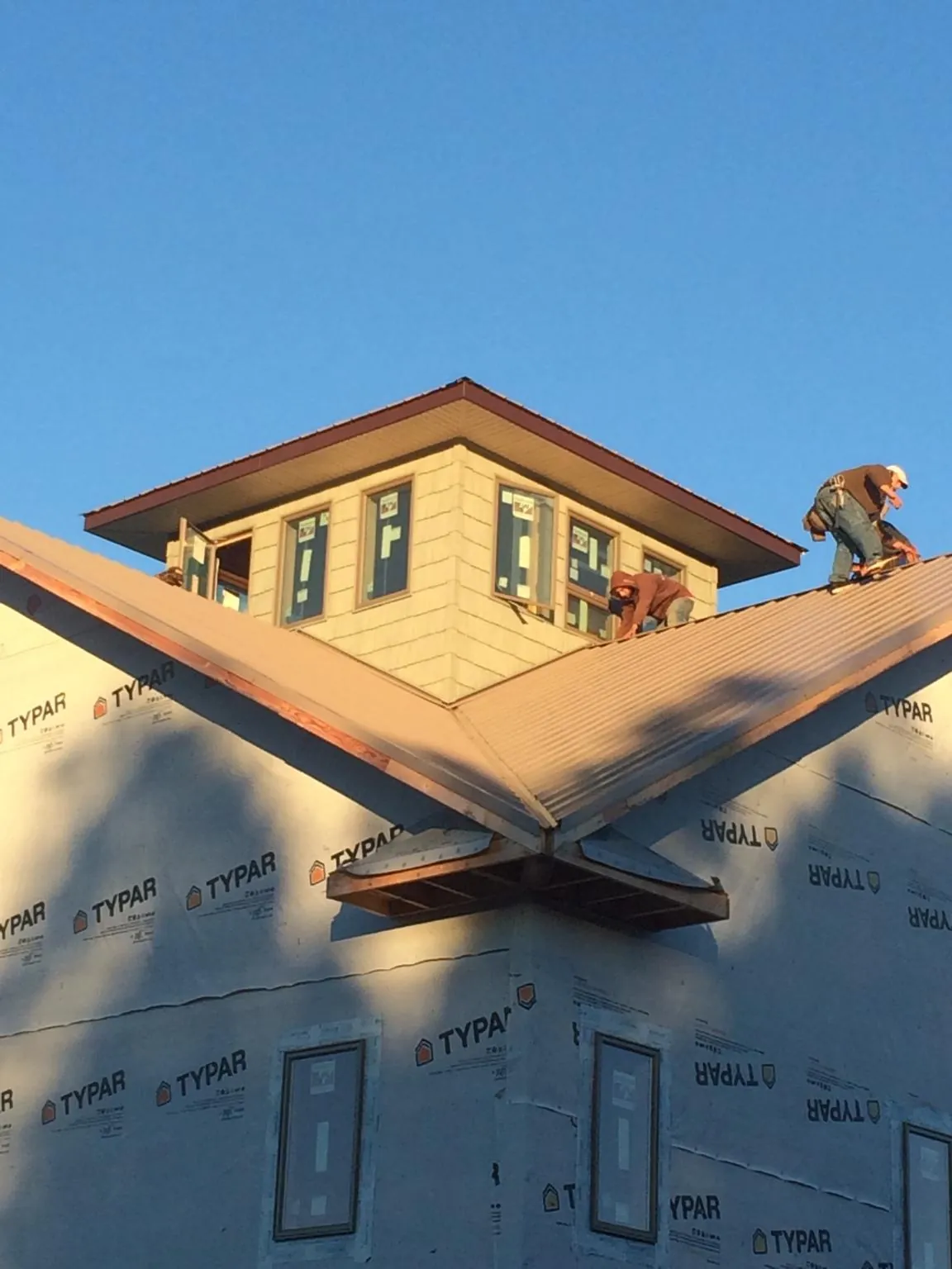Roofers working around a rooftop cupola on a new metal roof at sunset — Roof Waterproofing in Eagle Grove by Roofing Brothers